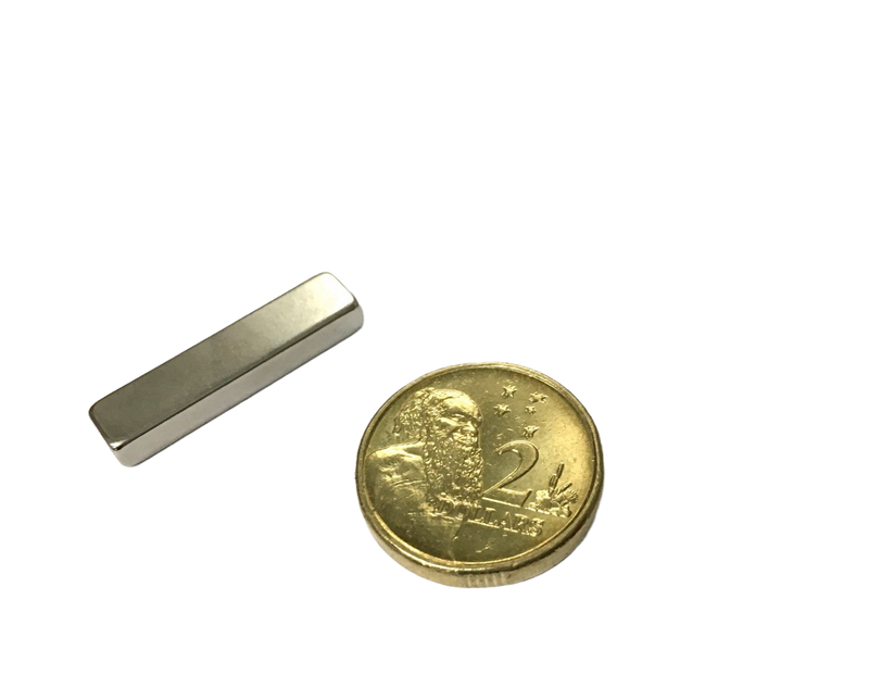 a small piece of metal sitting next to a coin