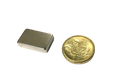 a gold coin next to a silver square magnet