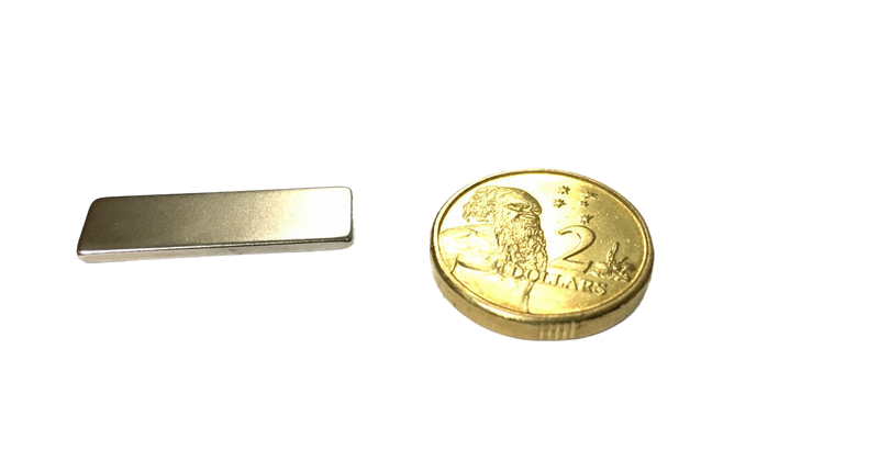a small metal bar next to a gold coin