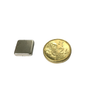 a small square metal object next to a gold coin