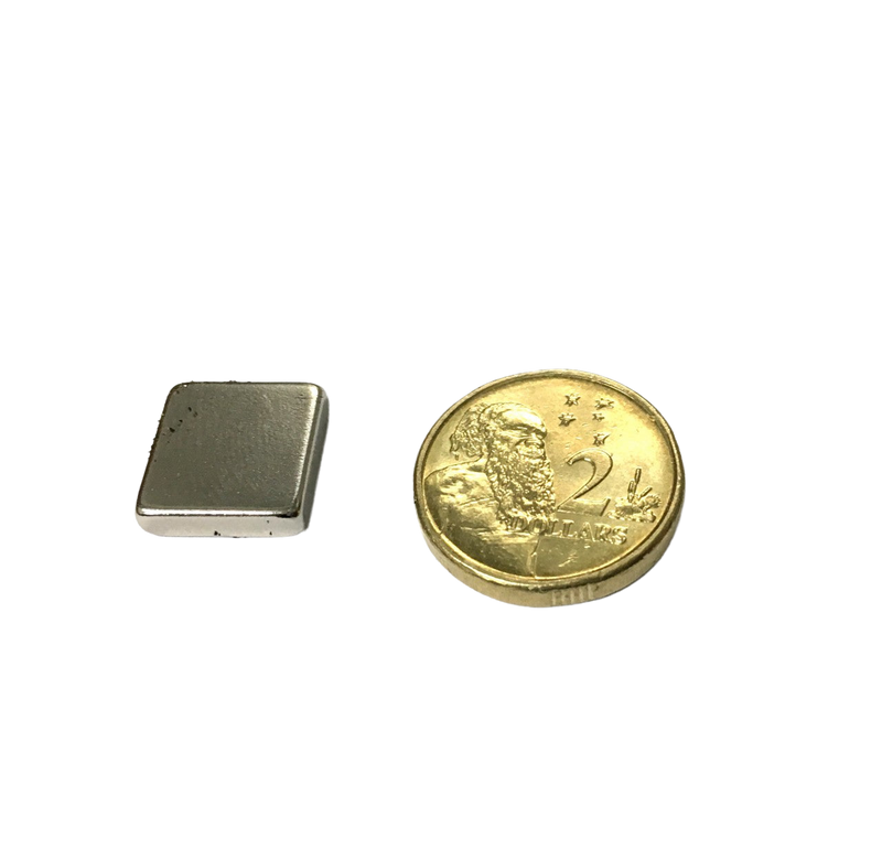 a small square metal object next to a gold coin