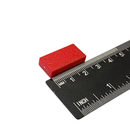 25.4mm x 12.7mm x 6.3mm red plastic coated neodymium block magnet shown beside a ruler for scale