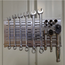Stainless steel magnetic tool panel on a steel shed wall holding spanners, sockets and ratchets