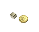 a small metal cube next to a gold coin
