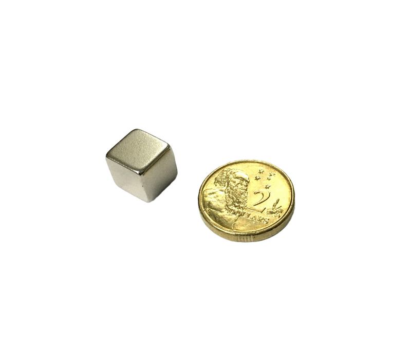 a small metal cube next to a gold coin